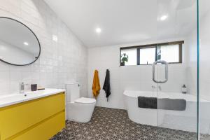 a bathroom with a tub and a toilet and a sink at Totara tree house in Nelson +6 photos