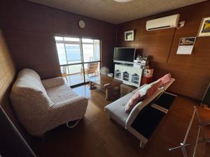 a living room with a couch and a tv at 民泊大浦崎荘 in Kure