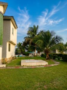 a house with a palm tree next to a building at Floyds Beach Resort & Spa in Nyanyanu