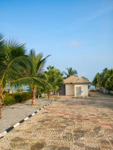 a road with palm trees and a building at Floyds Beach Resort & Spa in Nyanyanu