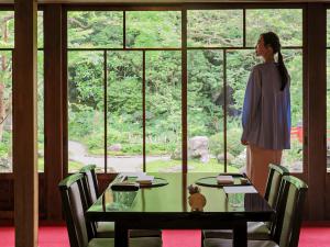 a woman standing next to a table looking out of a window at The Fujiya Hotel in Hakone