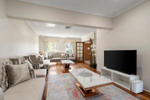 a living room with a couch and a flat screen tv at Drumbern Pool House Macquarie Links in Ingleburn