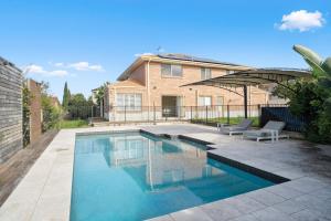 a swimming pool in front of a house at Drumbern Pool House Macquarie Links in Ingleburn