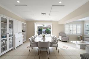 a kitchen and dining room with a white table and chairs at Drumbern Pool House Macquarie Links in Ingleburn