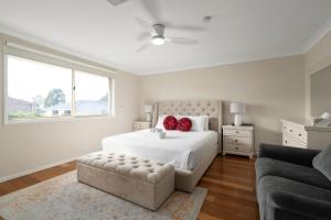 a white bedroom with a bed and a couch at Drumbern Pool House Macquarie Links in Ingleburn +36 photos