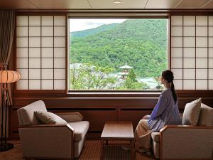 a woman sitting on a chair looking out of a window at The Fujiya Hotel in Hakone