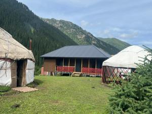 a couple of tents in front of a mountain at Forest Yurt House Altyn Arashan in Mineralʼnyy Istochnik Altyn-Arasan