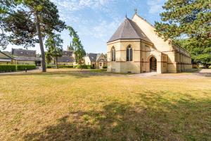 an old church with a grass field in front of it at The Apse in Stotfold