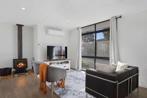 a living room with a couch and a tv and a fireplace at The Aurora House - BBQ Firepit Stargazing in Tea Tree +23 photos