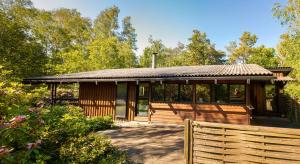 a wooden pavilion with a fence and trees at Architectdesigned 1976 Summer House Near Beach in Store Fuglede