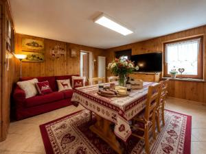 a living room with a table and a red couch at Maso Patrizia - Rifugio caldo tra le vette in Pieve Tesino