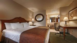a hotel room with a bed and a desk and a mirror at Best Western Miners Inn Yreka in Yreka