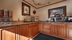 a kitchen with wooden cabinets and a microwave at Best Western Miners Inn Yreka in Yreka