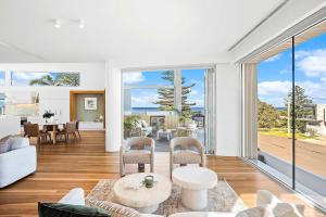 a living room with white furniture and large windows at The Grand Ocean Vista in Shellharbour