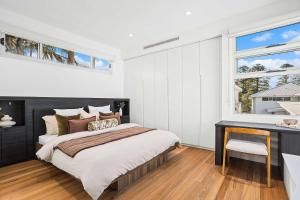 a bedroom with a bed and a desk and windows at The Grand Ocean Vista in Shellharbour