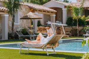 a woman laying in a hammock by a pool at Calarè Boutique Rooms - Adults Only in Cala Sinzias