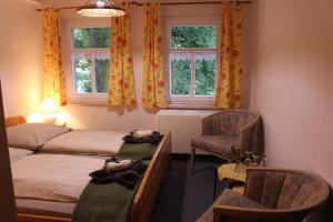 a bedroom with two beds and a chair and windows at HerrBerge Pilgerglück in Eibenstock