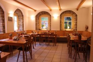a restaurant with wooden tables and chairs and windows at HerrBerge Pilgerglück in Eibenstock