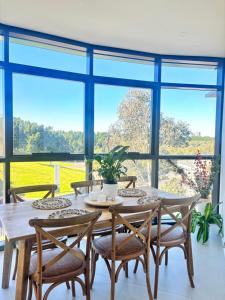 a dining room with a table and chairs and large windows at Floor-to-Ceiling Park View Oasis at Olympic Park Free Parking Sleeps 5 in Sydney