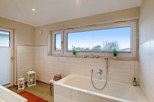 a bathroom with a bath tub and a window at Bauernhof Lafrenz, Ferienhäuser & Hofcafé in Fehmarn