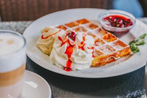 a white plate with waffles and ice cream and a drink at Bauernhof Lafrenz, Ferienhäuser & Hofcafé in Fehmarn