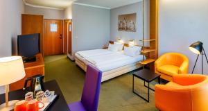 a hotel room with a bed and a chair at Best Western Parkhotel Brehna-Halle in Brehna
