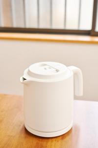a white slow cooker sitting on a wooden table at Kokonimo Niiza in Niizo