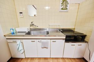 a kitchen with white cabinets and a sink at Kokonimo Niiza in Niizo +63 photos