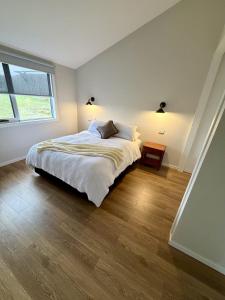 a white bedroom with a bed and a window at Devils Gap in Currie