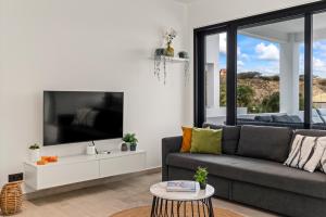 a living room with a gray couch and a large tv at Ocean View Apartment 384 Blue Bay in Dorp Sint Michiel