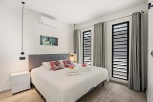 a white bedroom with a white bed and windows at Ocean View Apartment 384 Blue Bay in Dorp Sint Michiel