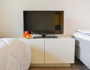 a tv on a white cabinet with a bowl of fruit at Helmiapartments Sotkamo in Sotkamo
