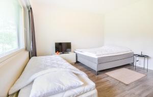a white bedroom with two beds and a tv at Helmiapartments Sotkamo in Sotkamo +14 photos