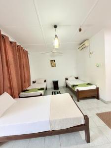 a room with three beds in a room at Terrel Residencies Gal Oya in Ampara
