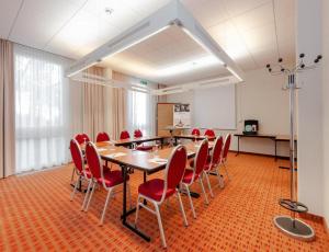 a conference room with a table and red chairs at Sunday Hotel Berlin City West in Berlin