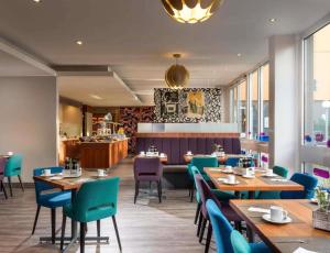 a restaurant with wooden tables and blue chairs at Sunday Hotel Berlin City West in Berlin