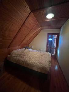 a bed in a room with a wooden ceiling at Templomzugi Fenyő Nyaraló in Gyomaendrőd