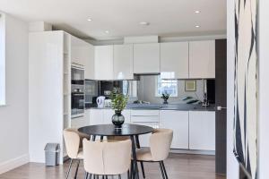 a kitchen with white cabinets and a table and chairs at Second Storey at Kew in Kew Bridge