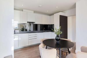 a kitchen with white cabinets and a table and chairs at Second Storey at Kew in Kew Bridge