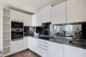 a kitchen with white cabinets and black appliances at Second Storey at Kew in Kew Bridge