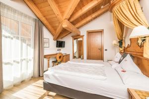 a bedroom with two beds and a large window at Hotel Flora in Selva di Val Gardena
