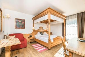 a bedroom with a canopy bed and a red couch at Hotel Flora in Selva di Val Gardena