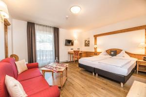 a hotel room with a bed and a red couch at Hotel Flora in Selva di Val Gardena