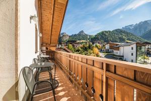 a balcony with tables and chairs and a view of mountains at Hotel Flora in Selva di Val Gardena