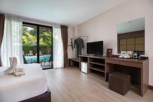 a bedroom with a bed and a desk with a television at The BELL in Nai Yang Beach