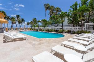 a swimming pool with white lounge chairs next to a resort at Wyndham Deerfield Beach Resort in Deerfield Beach