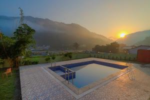 a swimming pool with the sunset in the background at Prideinn Luxury Resort in Rishīkesh +9 photos