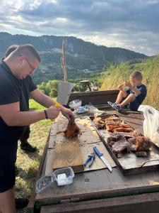 a man cooking meat on a table with two boys at Ранч ДИМ in Ivanjica
