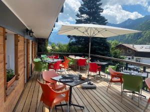 a deck with tables and chairs and an umbrella at Terra-Beka Lodge in La Chapelle-dʼAbondance