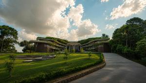 a building with a green roof on a grass field at Mountree Munnar by Kondody Hotels in Anachal